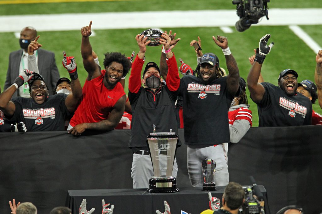 OSU head coach Ryan Day holds up the championship trophy alongside MVP Trey Sermon after the Buckeyes won 22-10 in the game between Ohio State and Northwestern in the Big 10 Championship game at Lucas Oil Stadium in Indianapolis, Indiana on Saturday, December 19, 2020. | Image Credit - David Petkiewicz/Cleveland.com