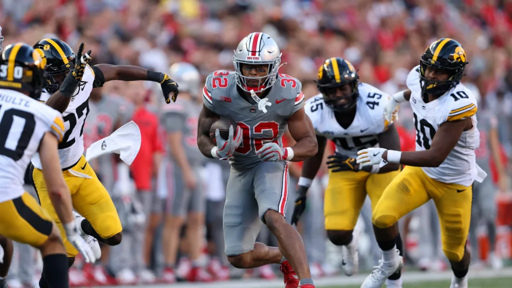 Oct 5, 2024; Columbus, Ohio, USA; Ohio State Buckeyes running back TreVeyon Henderson (32) runs the ball against Iowa Hawkeyes linebacker Nick Jackson (10) and defensive back Jermari Harris (27) during the fourth quarter at Ohio Stadium. Mandatory Credit: Joseph Maiorana-Imagn Images / Joseph Maiorana-Imagn Images