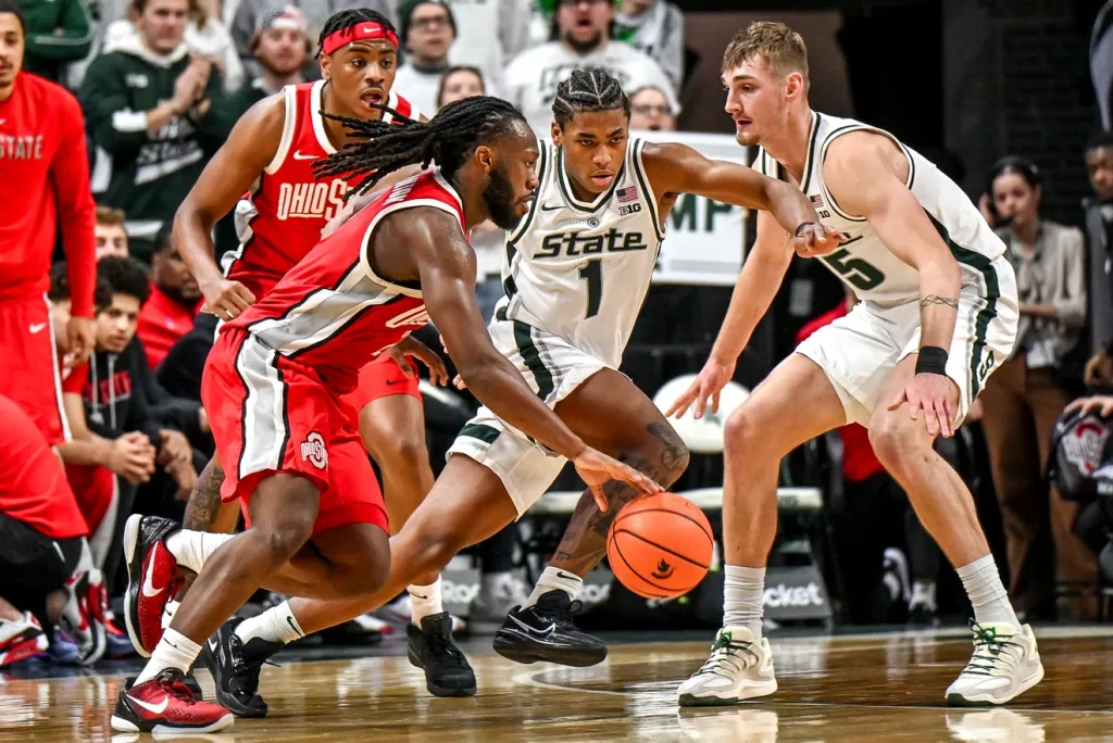 Michigan State's Jeremy Fears Jr., center, defends against Ohio State's Bruce Thornton, left, during the second half on Sunday, Feb. 22, 2026, at the Breslin Center in East Lansing. | Nick King/Lansing State Journal