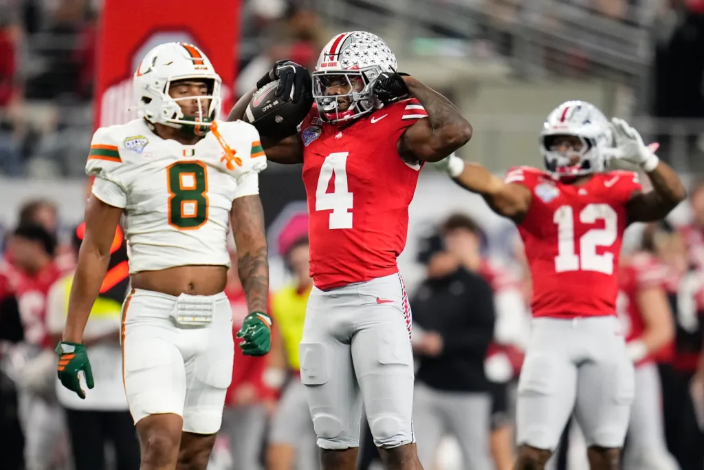 Ohio State Buckeyes wide receiver Jeremiah Smith (4) celebrates a first down beside Miami Hurricanes defensive back Jakobe Thomas (8) during the Cotton Bowl at AT&T Stadium in Arlington, Texas for the College Football Playoff quarterfinal game on Dec. 31, 2025. Ohio State lost 24-14. | Adam Cairns/Columbus Dispatch