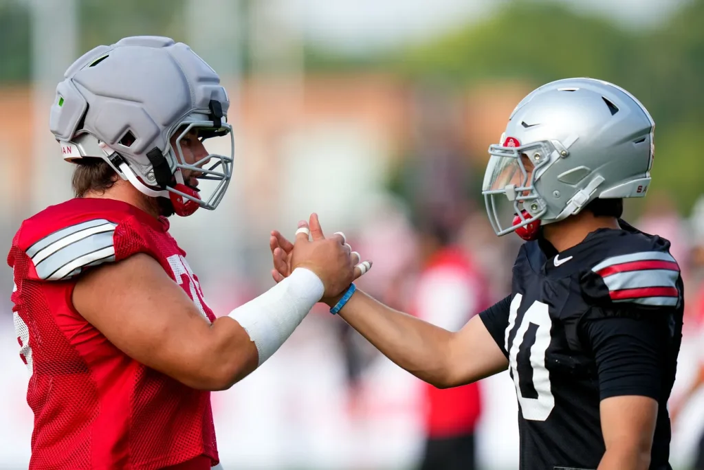Ohio State Buckeyes offensive lineman Carson Hinzman (75) shakes hands with quarterback Julian Sayin (10) during the third day of training camp at the Woody Hayes Athletic Center on Aug. 8, 2026 in Columbus, Ohio. | Samantha Madar/Columbus Dispatch